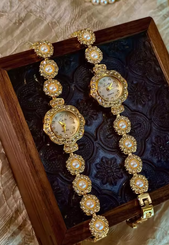 Gold ladies bracelet watch with freshwater pearl and pav´e crystal
flower link chain, scalloped floral case and champagne dial by Le Belle Heure