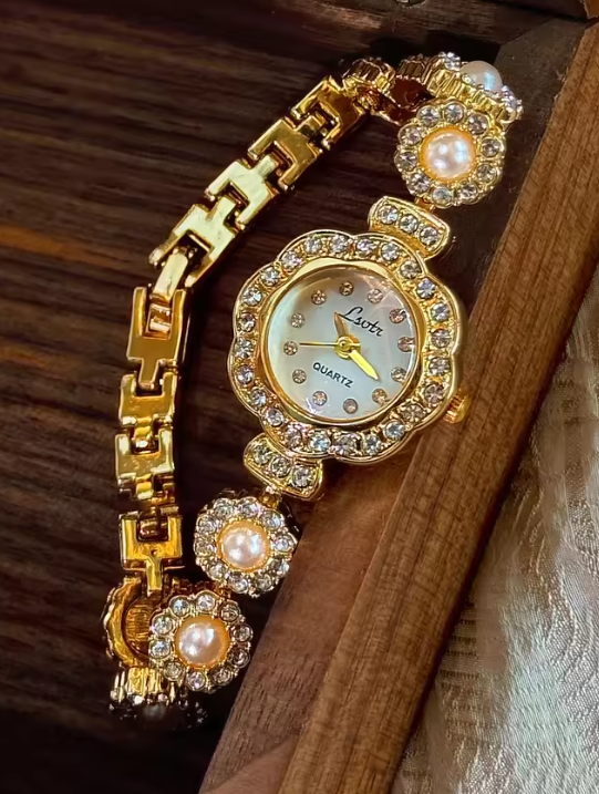 Gold ladies bracelet watch with freshwater pearl and pav´e crystal
flower link chain, scalloped floral case and champagne dial by Le Belle Heure