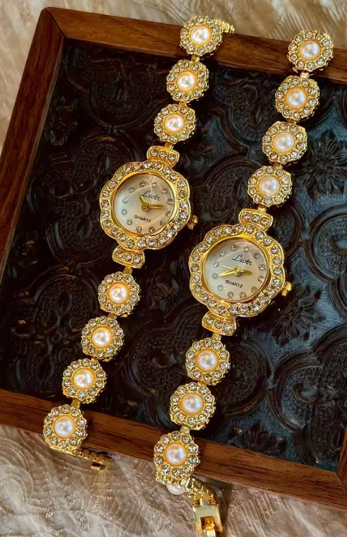 Gold ladies bracelet watch with freshwater pearl and pav´e crystal
flower link chain, scalloped floral case and champagne dial by Le Belle Heure
