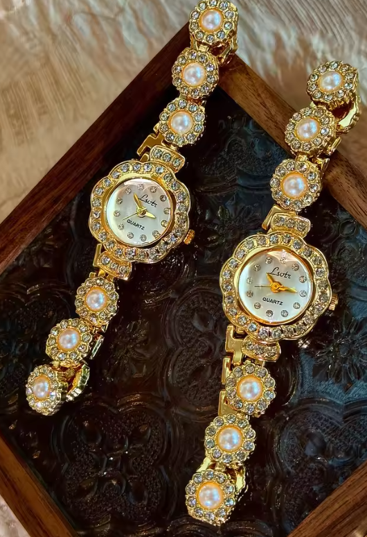 Gold ladies bracelet watch with freshwater pearl and pav´e crystal
flower link chain, scalloped floral case and champagne dial by Le Belle Heure