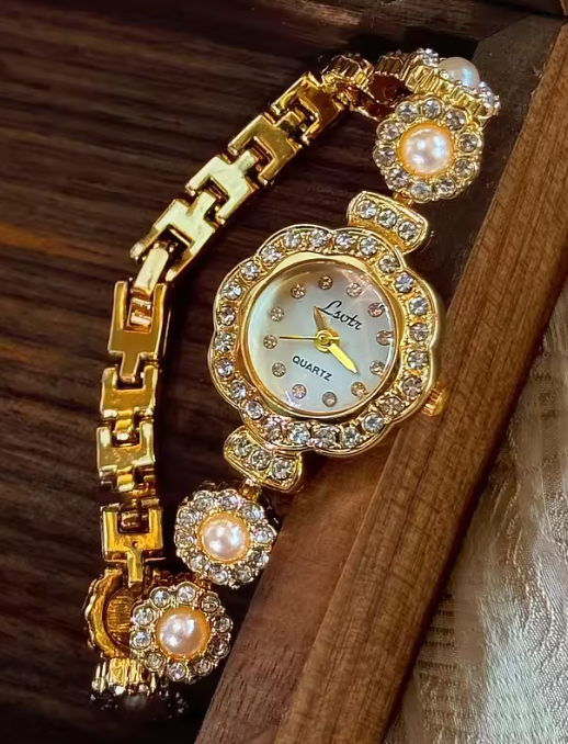 Gold ladies bracelet watch with freshwater pearl and pav´e crystal
flower link chain, scalloped floral case and champagne dial by Le Belle Heure