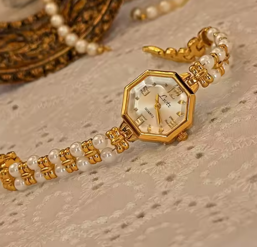 Le Belle Heure women’s gold octagonal quartz watch with pearl and gold bracelet strap on vintage surface