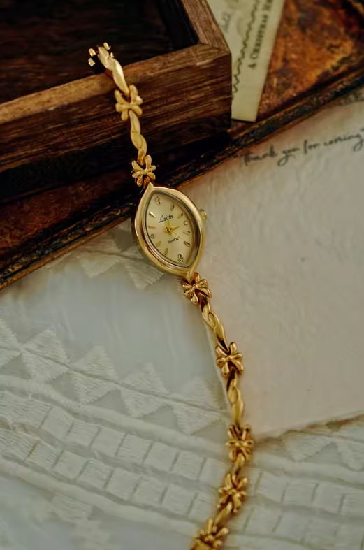 Gold twisted rope and flower knot chain bracelet watch with champagne oval dial and diamond-like hour markers for women by Le Belle Heure