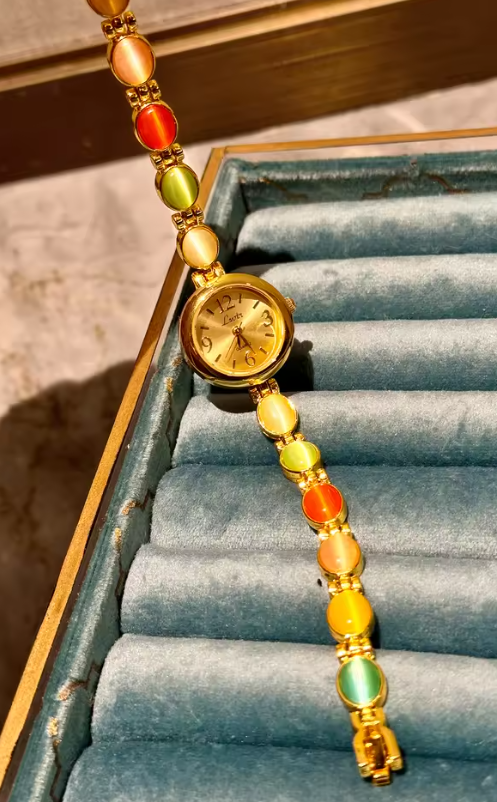 Gold-tone round dial women’s bracelet watch with multicolour peach, green and red oval gemstones by Le Belle Heure