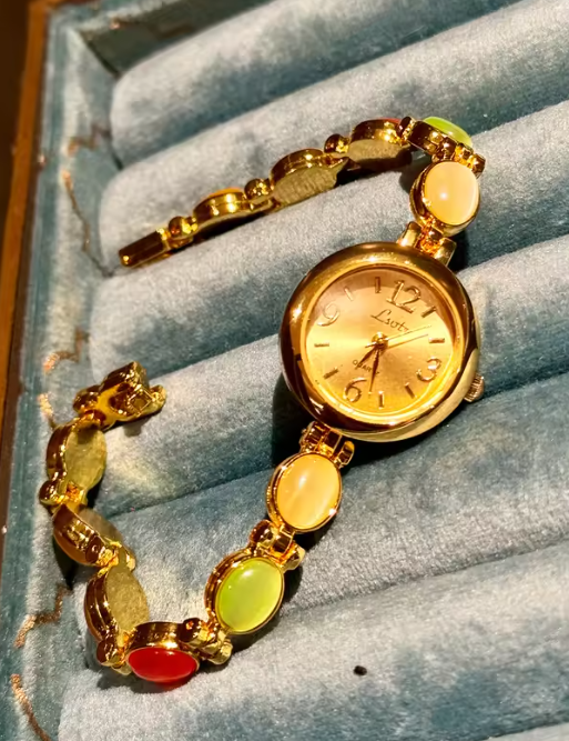 Gold-tone round dial women’s bracelet watch with multicolour peach, green and red oval gemstones by Le Belle Heure