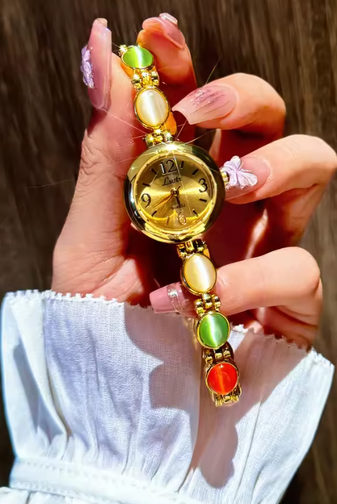 Gold-tone round dial women’s bracelet watch with multicolour peach, green and red oval gemstones by Le Belle Heure