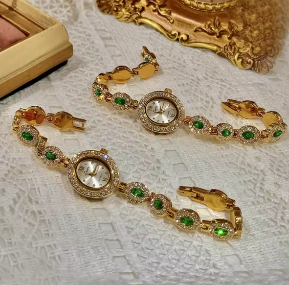Gold bracelet watch with emerald green oval faceted gemstones set in
white pave crystal halos and champagne oval dial for women by Le Belle Heure