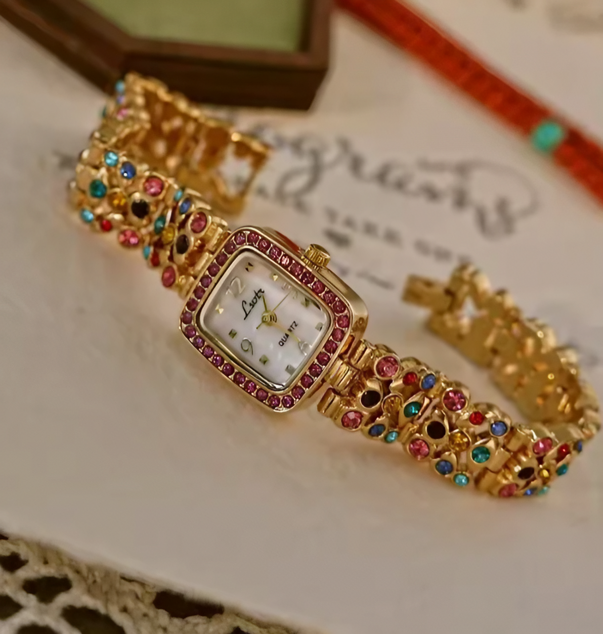 Gold-tone women’s bracelet watch with multicolour rhinestones and pink crystal bezel by Le Belle Heure