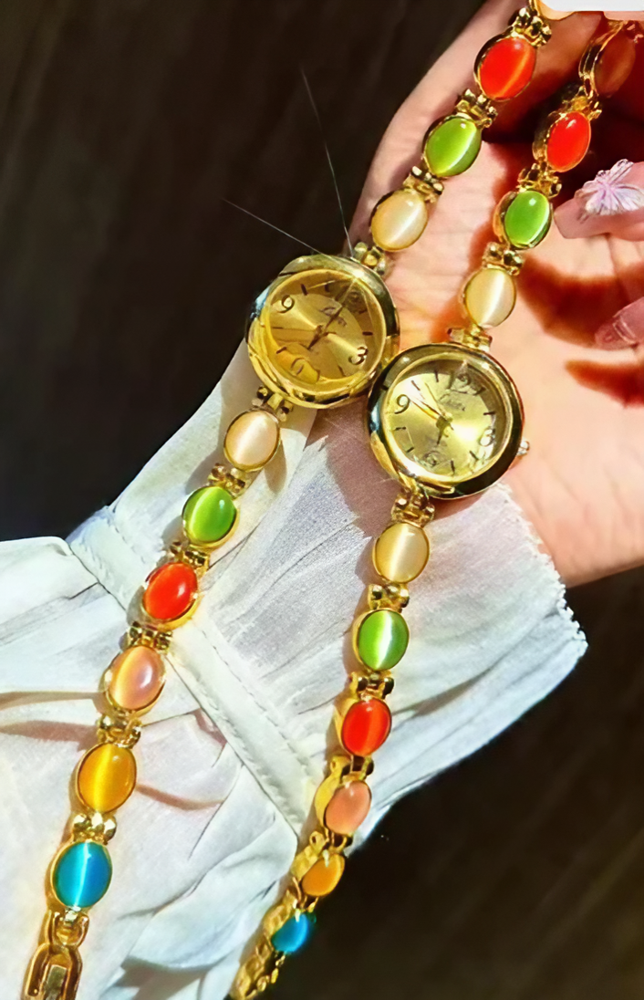 Gold-tone round dial women’s bracelet watch with multicolour peach, green and red oval gemstones by Le Belle Heure