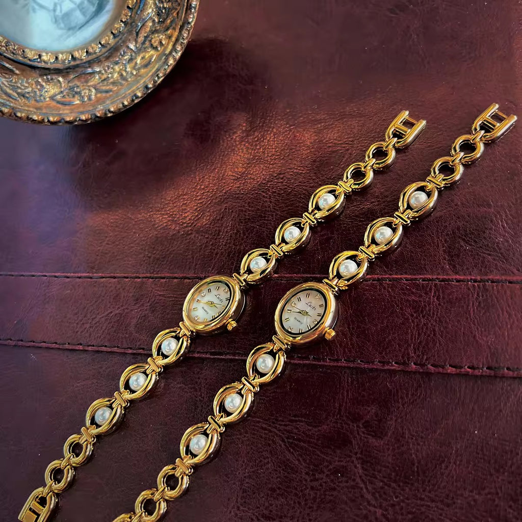 Gold oval bracelet watch with freshwater pearl eye-link chain and
champagne dial with gold hour markers for women by Le Belle Heure