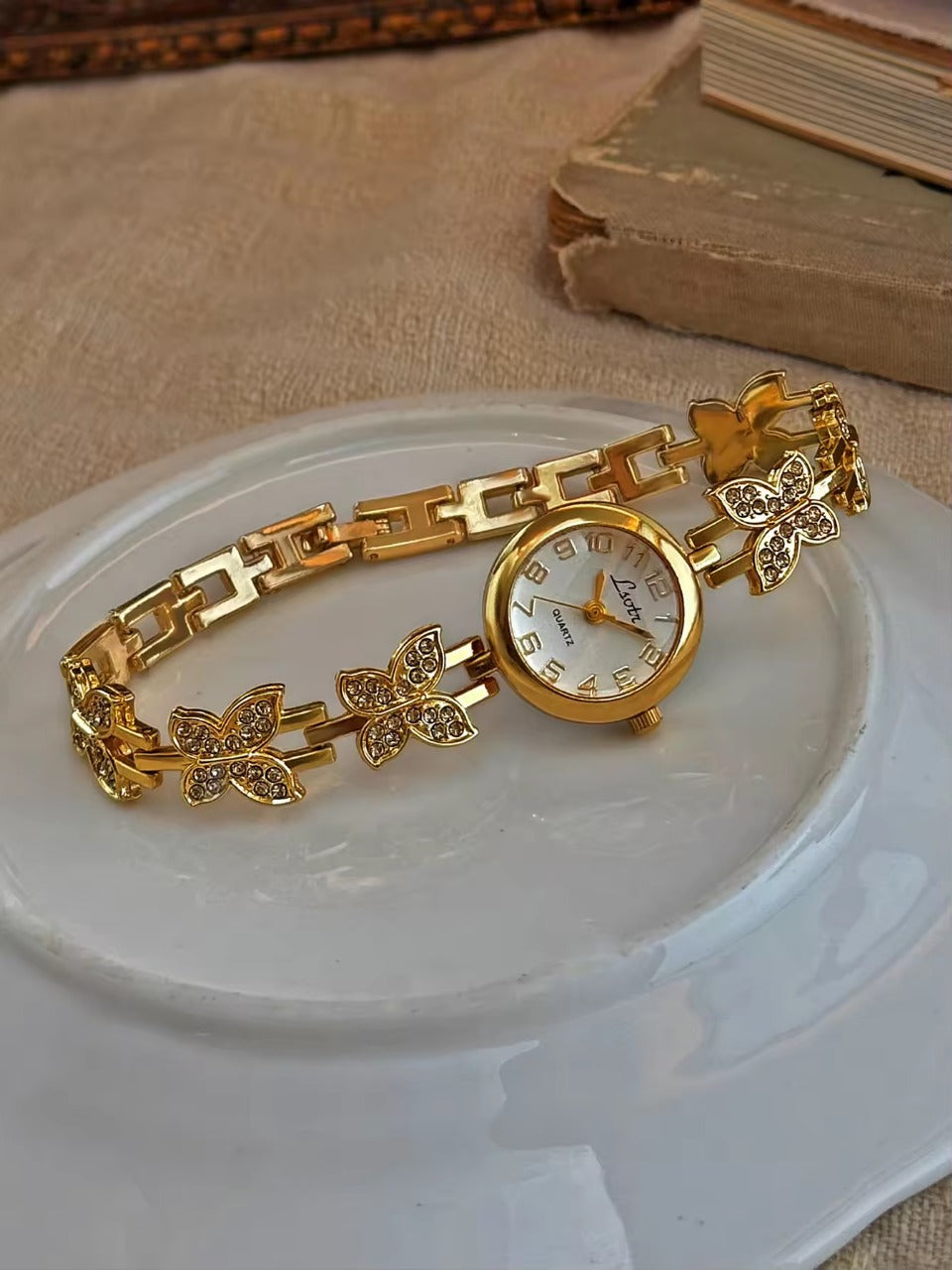 Gold crystal rhinestone butterfly link bracelet watch with mother-of-pearl round dial and Arabic numerals for women by Le Belle Heure