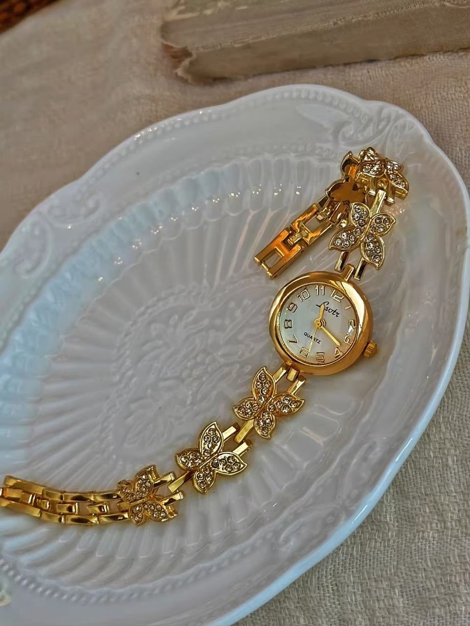 Gold crystal rhinestone butterfly link bracelet watch with mother-of-pearl round dial and Arabic numerals for women by Le Belle Heure