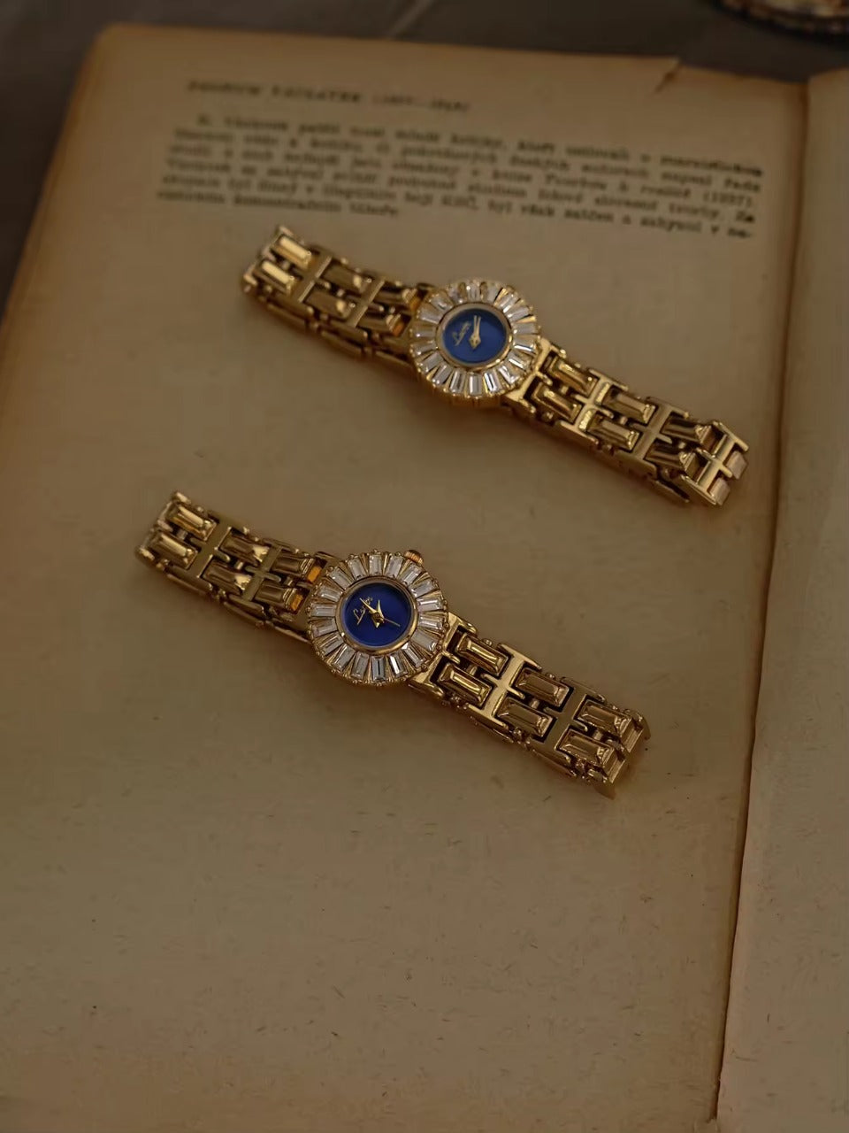 Gold bracelet watch with navy blue dial and baguette crystal starburst
halo bezel on wide panther chain band for women by Le Belle Heure