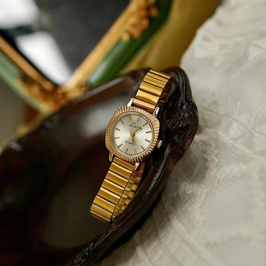 gold ribbed coin-edge bezel flex band watch with white oval dial for women by Le Belle Heure