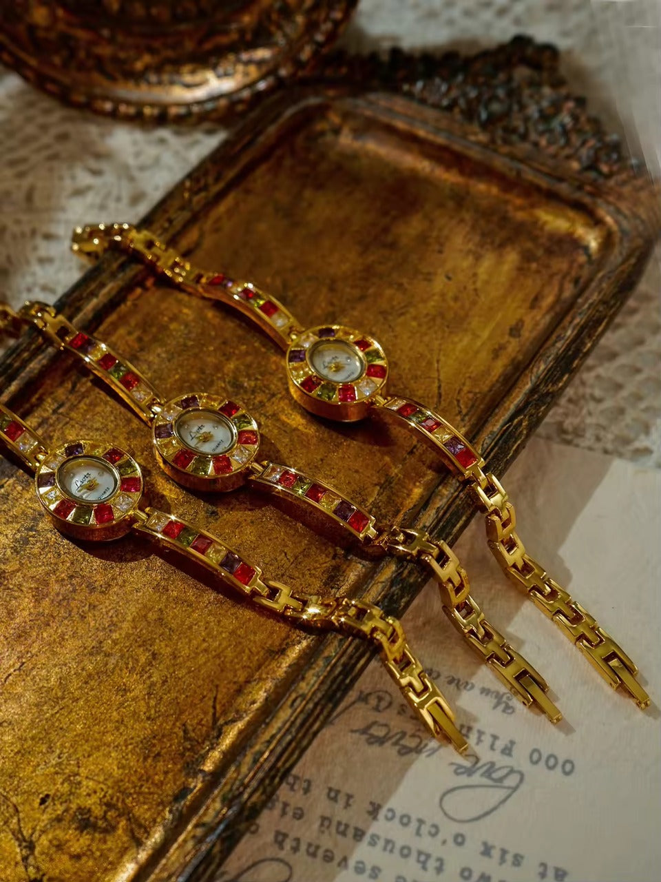 Gold oval dial ladies bracelet watch with multicolour ruby, amber, green and crystal square gemstone bezel and coloured link chain by Le Belle Heure