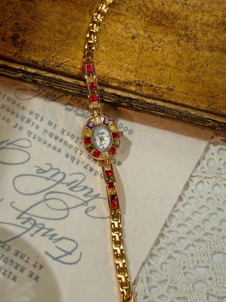 Gold oval dial ladies bracelet watch with multicolour ruby, amber, green and crystal square gemstone bezel and coloured link chain by Le Belle Heure