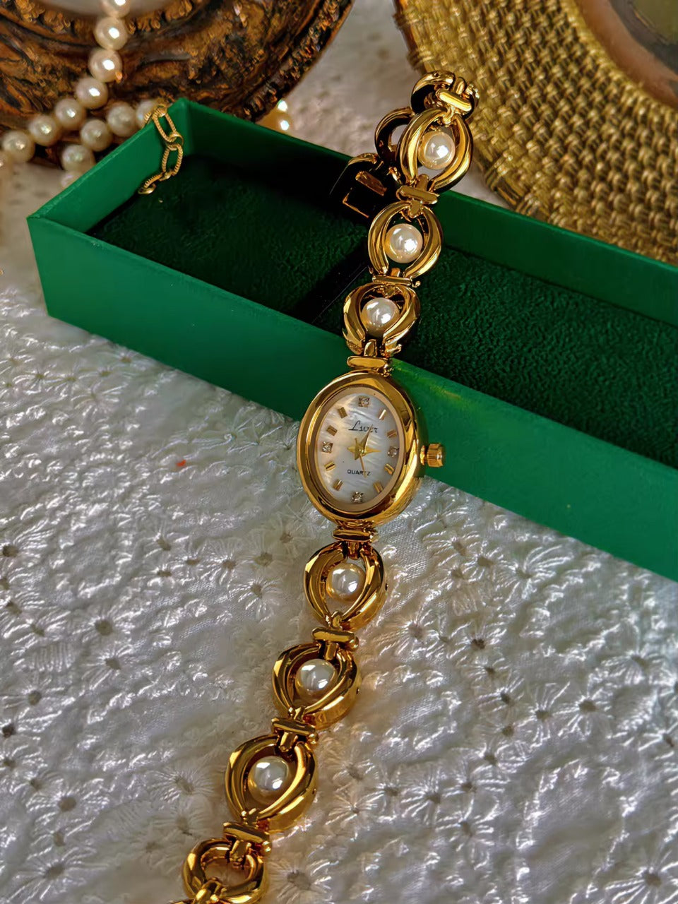 Gold oval bracelet watch with freshwater pearl eye-link chain and
champagne dial with gold hour markers for women by Le Belle Heure