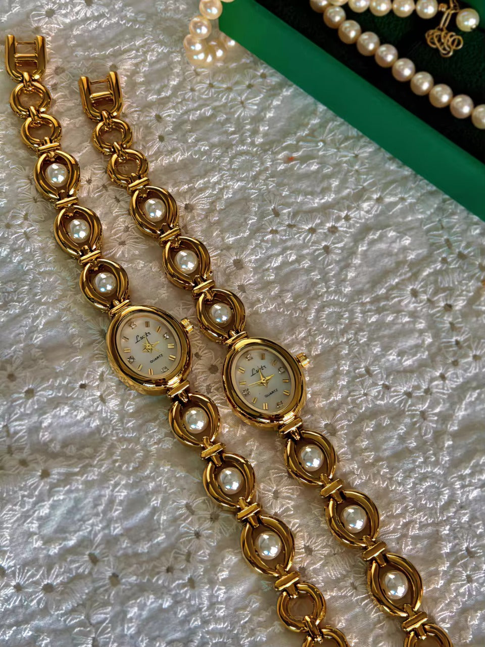 Gold oval bracelet watch with freshwater pearl eye-link chain and
champagne dial with gold hour markers for women by Le Belle Heure