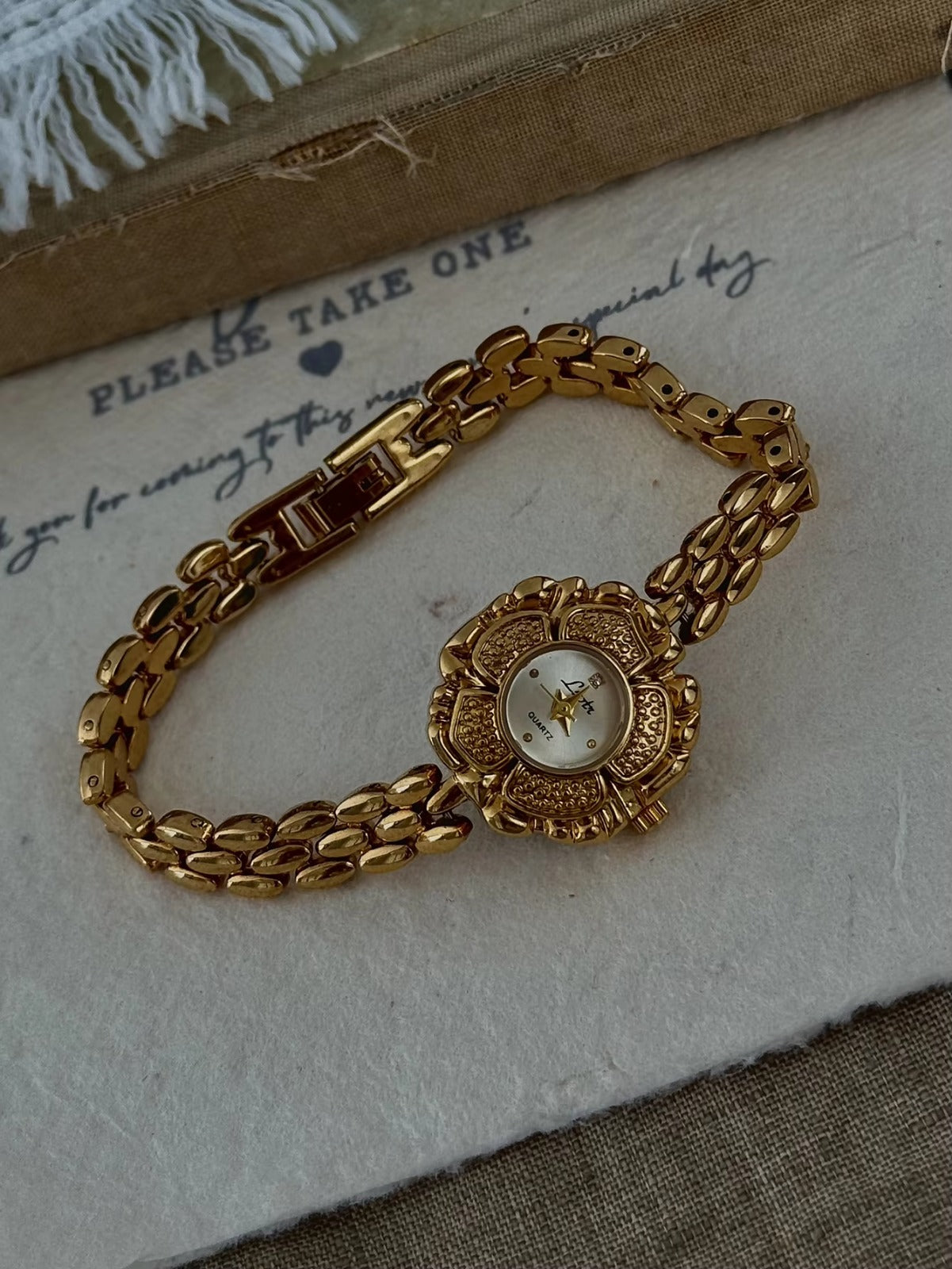 Bold gold-tone panther chain link bracelet band on women’s vintage-style flower watch