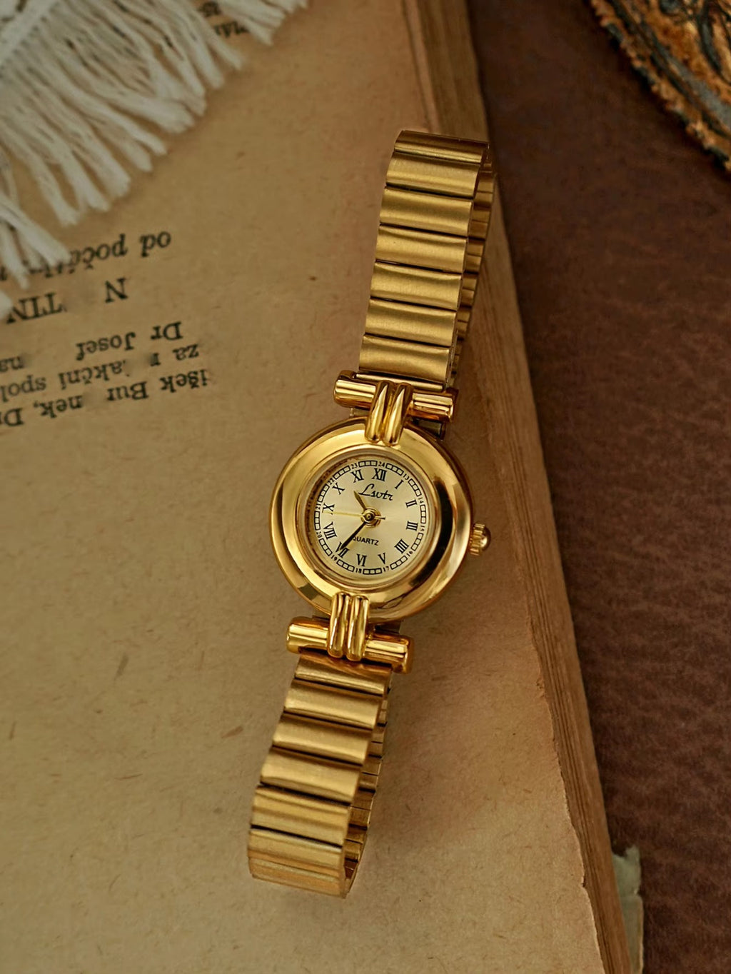 Gold domed oval watch with Roman numeral champagne dial, double
bar lug case connectors and wide ribbed accordion flex band for women by Le Belle Heure