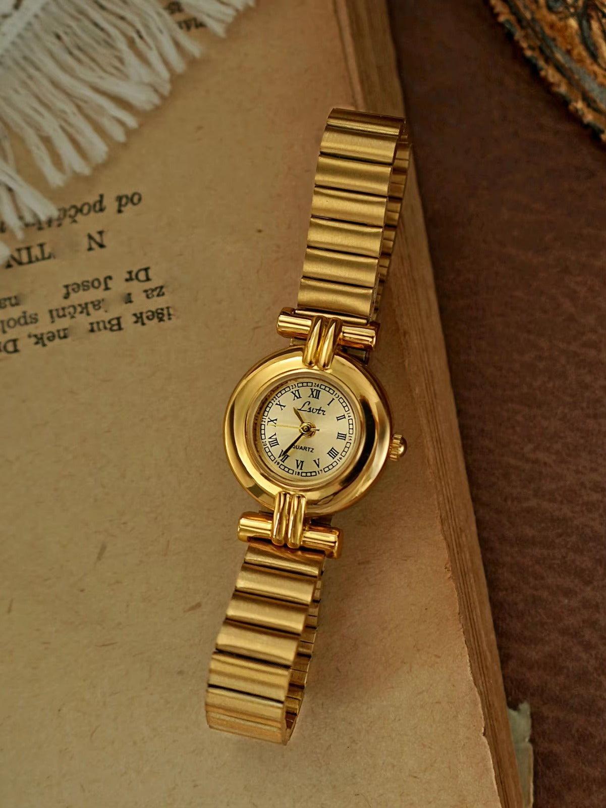 Gold domed oval watch with Roman numeral champagne dial, double
bar lug case connectors and wide ribbed accordion flex band for women by Le Belle Heure