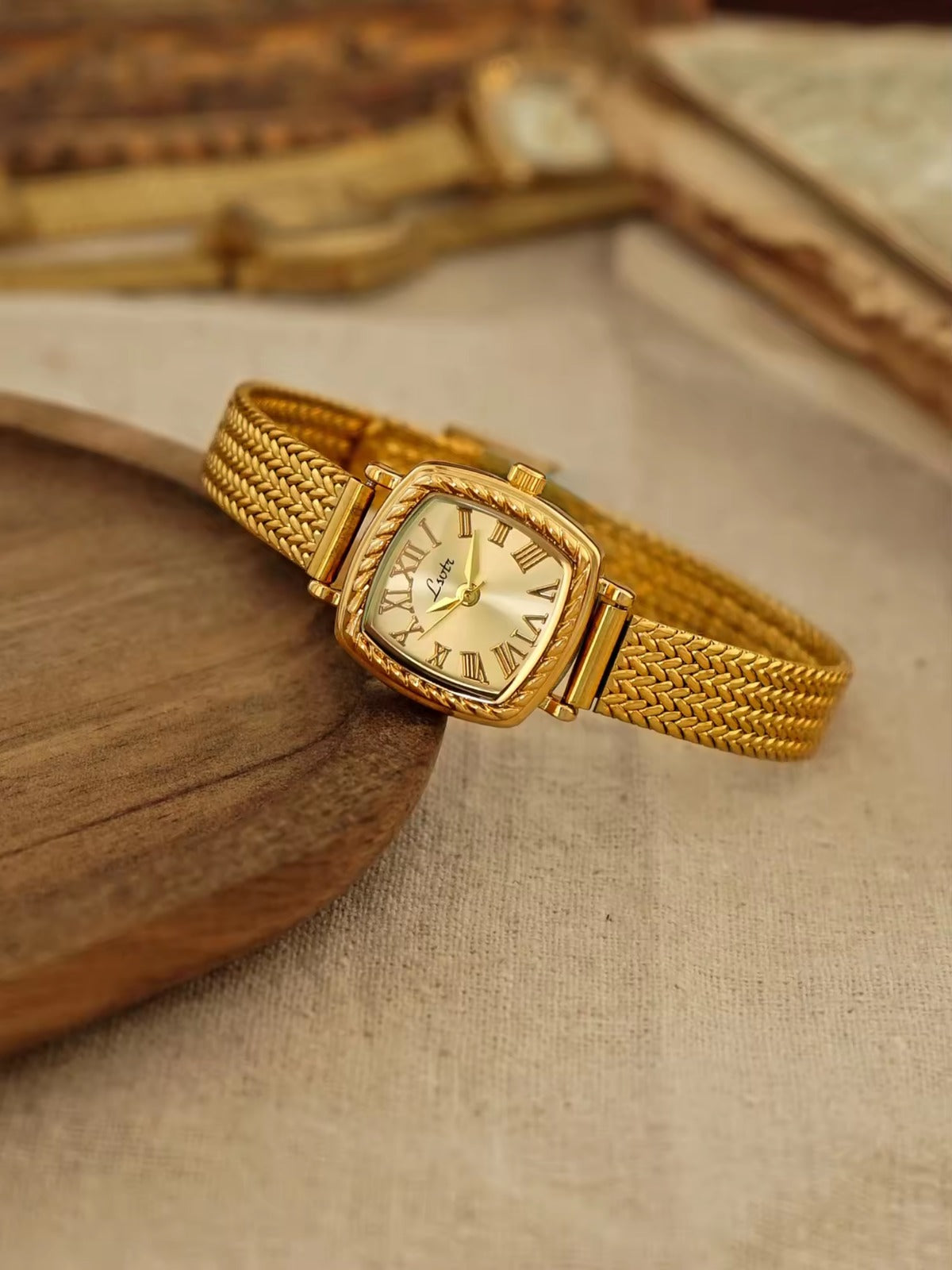 Gold tonneau cushion-shaped watch with engraved rope-twist bezel,
Roman numeral champagne sunburst dial and wide braided herringbone mesh bracelet for women by Le Belle Heure