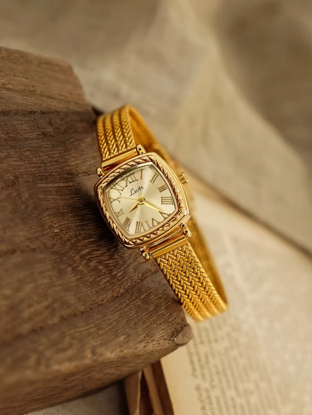 Gold tonneau cushion-shaped watch with engraved rope-twist bezel,
Roman numeral champagne sunburst dial and wide braided herringbone mesh bracelet for women by Le Belle Heure