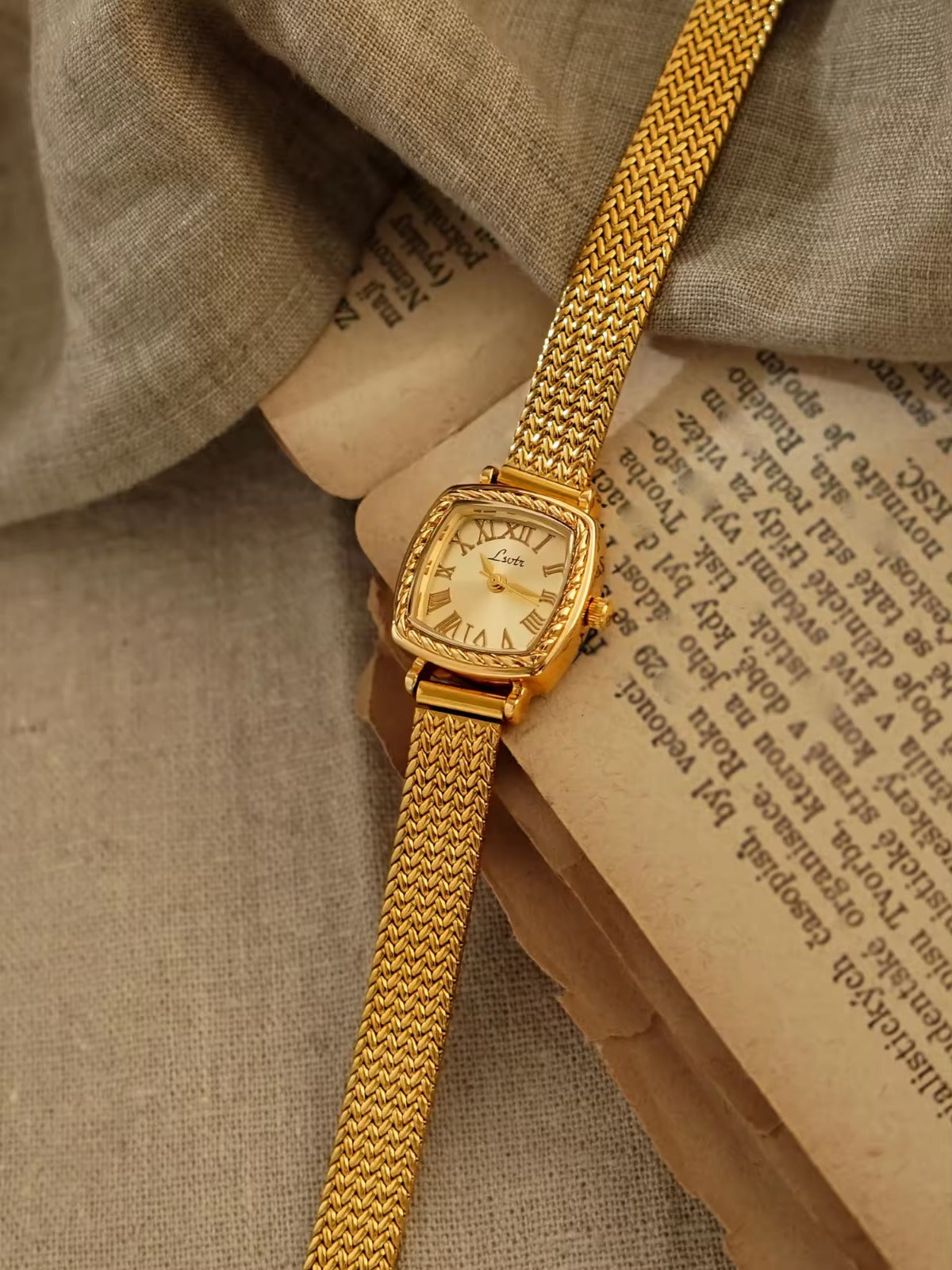 Gold tonneau cushion-shaped watch with engraved rope-twist bezel,
Roman numeral champagne sunburst dial and wide braided herringbone mesh bracelet for women by Le Belle Heure