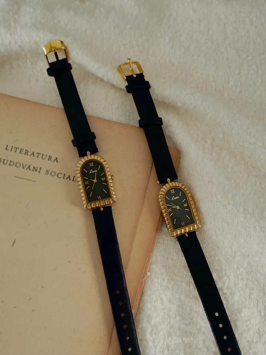 Gold arch-shaped case watch with scalloped fluted bezel, black Roman
numeral dial with gold hour markers and slim black leather strap with gold buckle
for women by Le Belle Heure