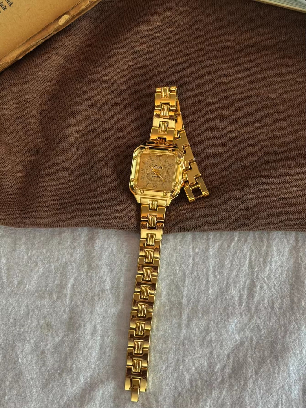 Gold square Roman numeral textured sunburst dial watch with screw
corner accents and wide structured woven link chain bracelet for women by Le Belle Heure