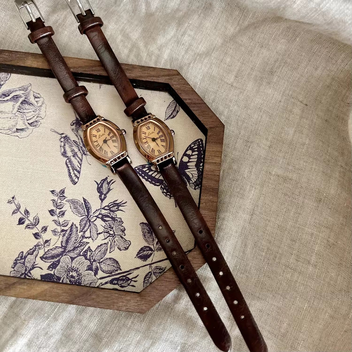 Rose gold tonneau watch with crystal-set upper and lower bezel, ivory champagne Roman numeral dial and slim dark chocolate brown leather strap for women by Le Belle Heure