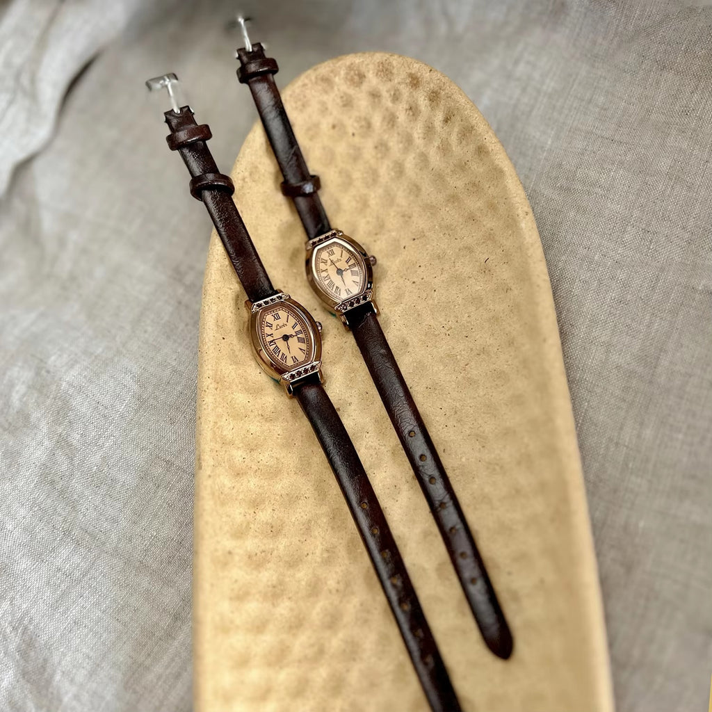 Rose gold tonneau watch with crystal-set upper and lower bezel, ivory champagne Roman numeral dial and slim dark chocolate brown leather strap for women by Le Belle Heure