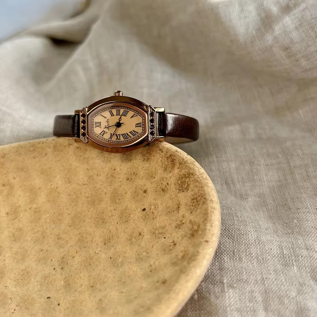 Rose gold tonneau watch with crystal-set upper and lower bezel, ivory champagne Roman numeral dial and slim dark chocolate brown leather strap for women by Le Belle Heure