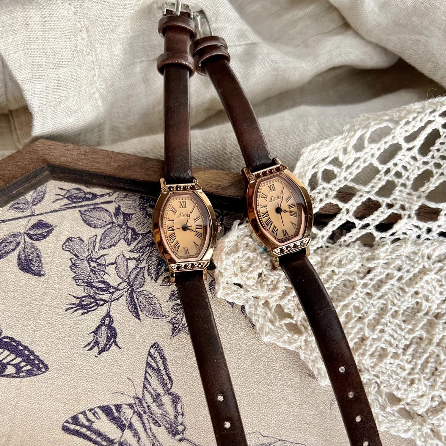 Rose gold tonneau watch with crystal-set upper and lower bezel, ivory champagne Roman numeral dial and slim dark chocolate brown leather strap for women by Le Belle Heure