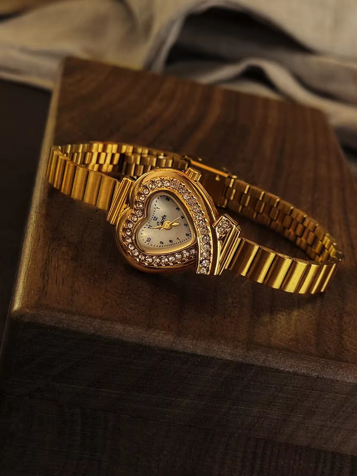 Gold heart-shaped quartz watch with double pav´e crystal halo bezel,
white dial, crossed bow lugs and wide ribbed gold flex bracelet for women by Le Belle Heure