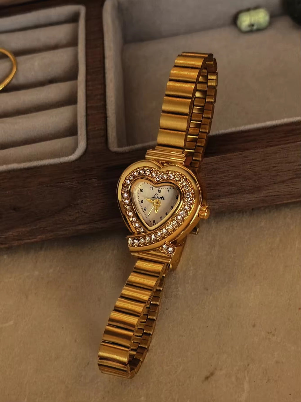 Gold heart-shaped quartz watch with double pav´e crystal halo bezel,
white dial, crossed bow lugs and wide ribbed gold flex bracelet for women by Le Belle Heure