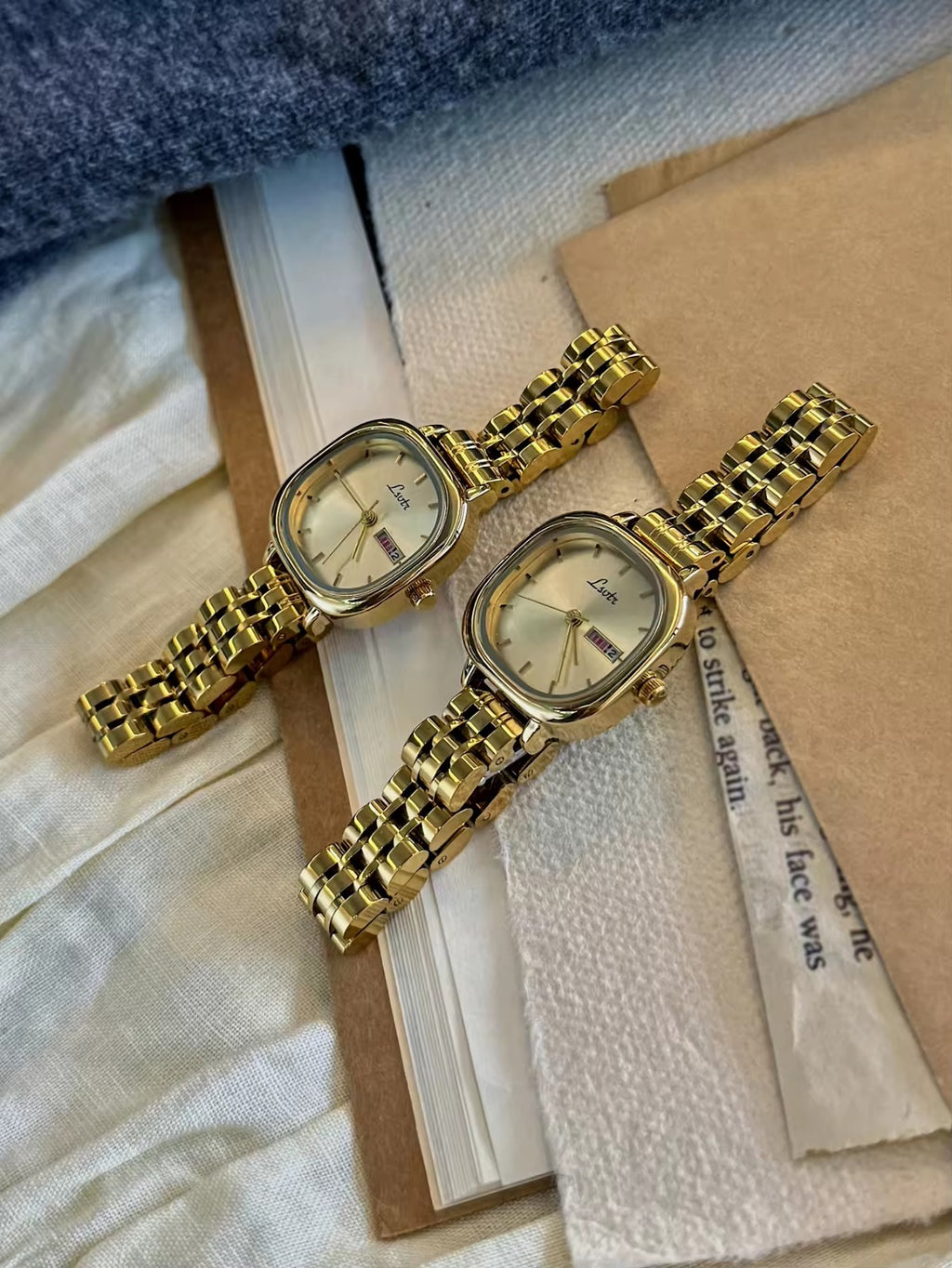 Gold square couple watch set with champagne dial and day-date display on gold stainless steel bracelet - Le Belle Heure