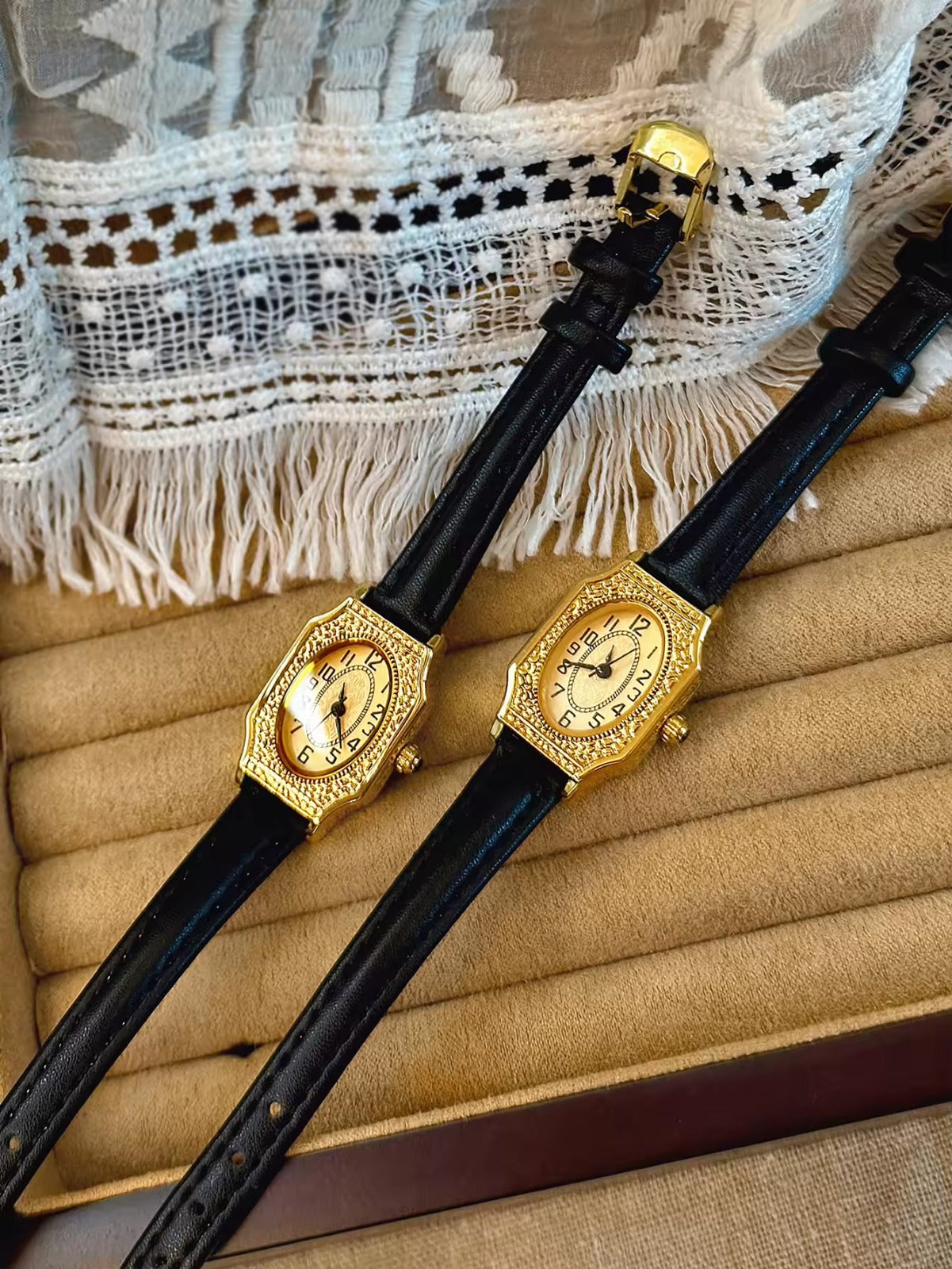 Two women’s vintage gold octagonal watches with engraved filigree bezels, champagne dials, and slim black leather straps on a velvet display tray — Le Belle Heure