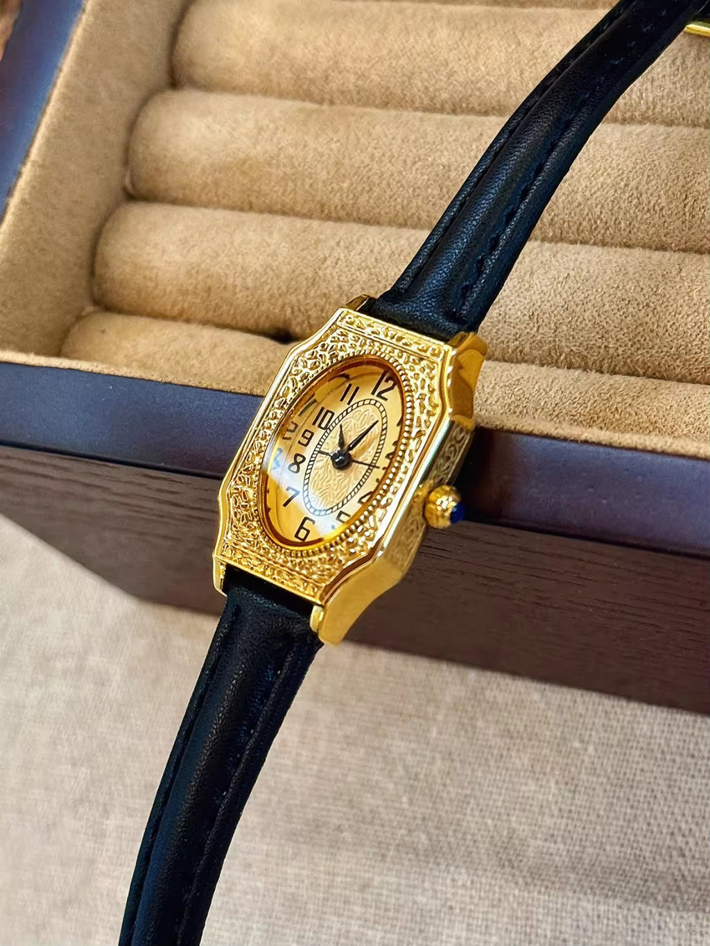 Two women’s vintage gold octagonal watches with engraved filigree bezels, champagne dials, and slim black leather straps on a velvet display tray — Le Belle Heure