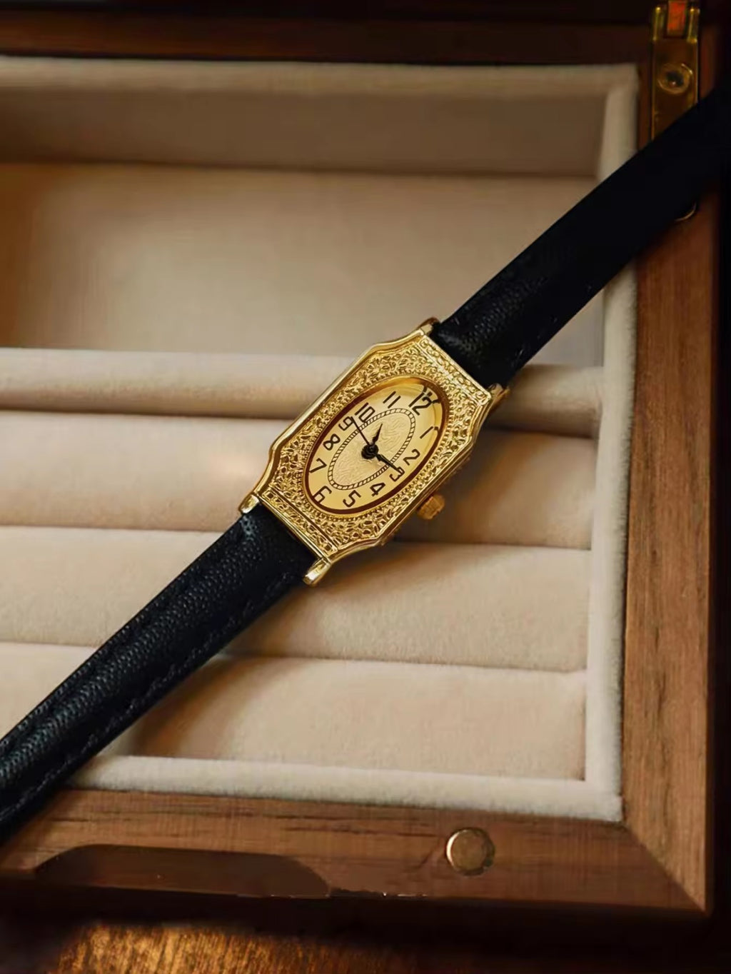 Two women’s vintage gold octagonal watches with engraved filigree bezels, champagne dials, and slim black leather straps on a velvet display tray — Le Belle Heure